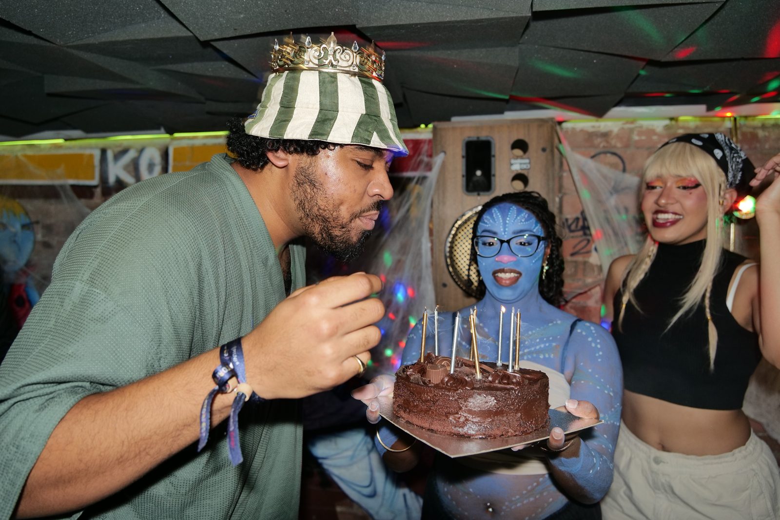 An attendee blowing out candles on a birthday cake at the Anime House Party