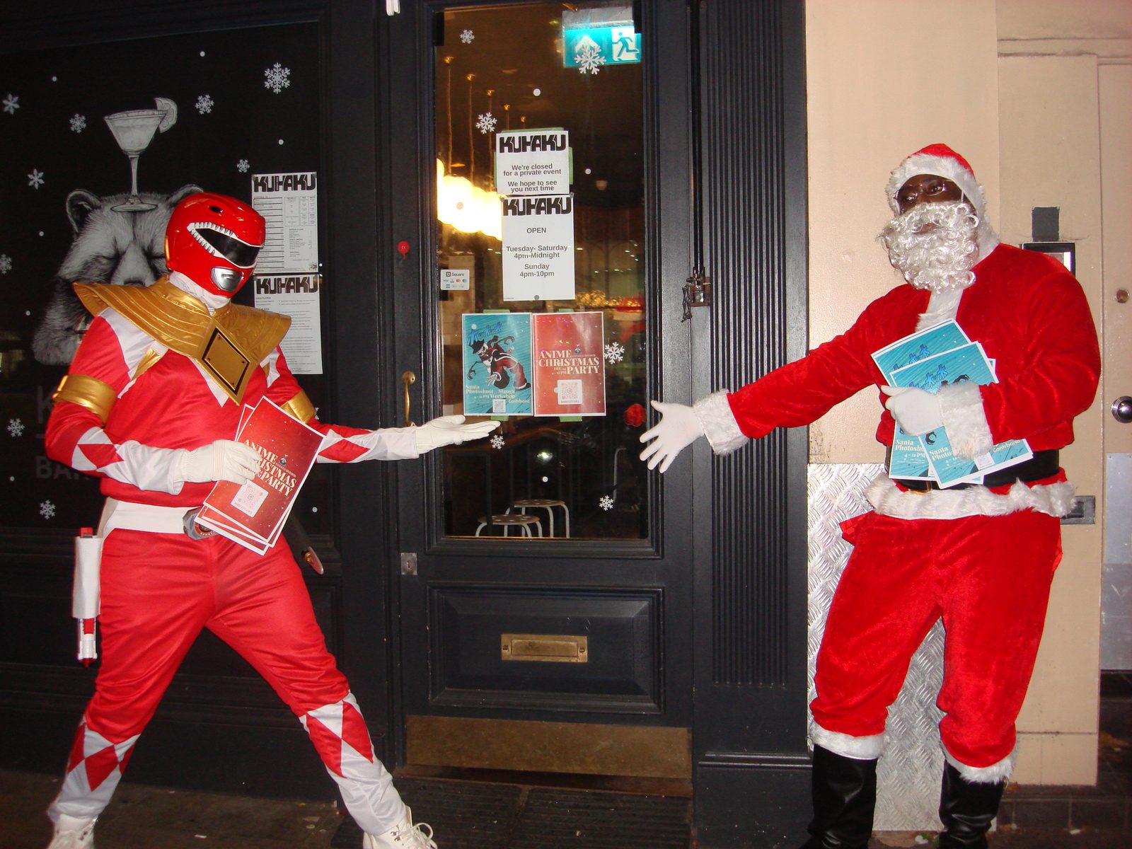 Attendees in Santa and Power Ranger costumes posing outside a venue at the Christmas party