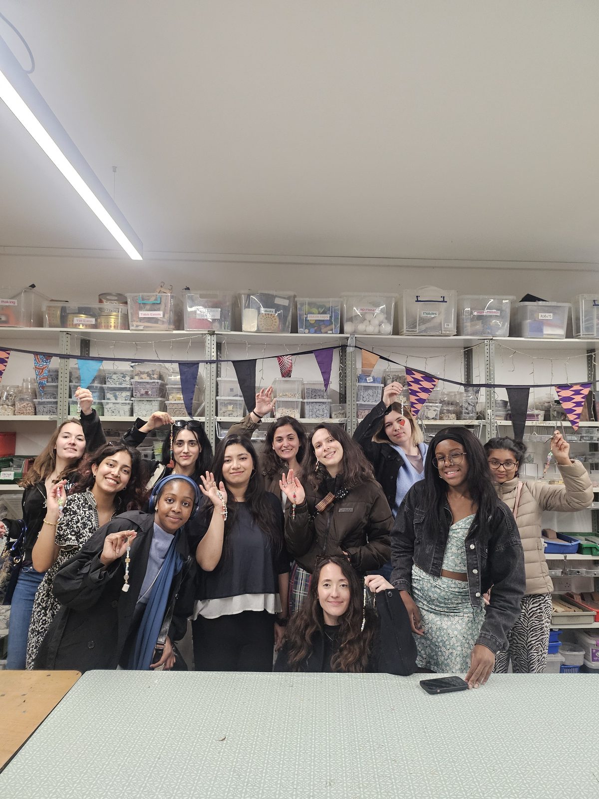 Attendees showing off handmade bracelets at a jewelry workshop